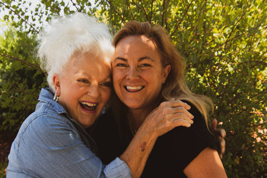 Two women hug and smile outside
