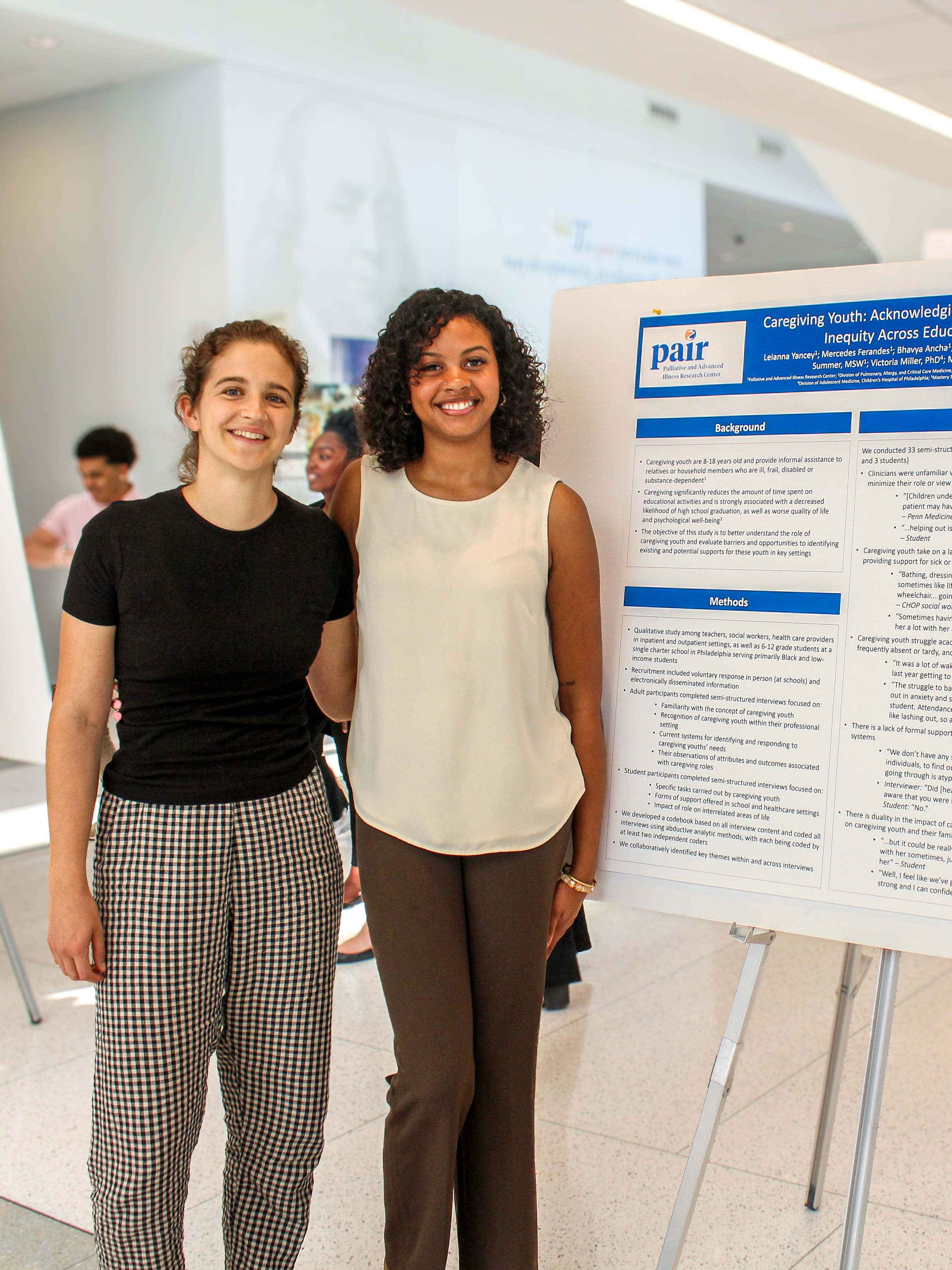Former staff Amy Summer and student Leianna Yancey standing next to a poster on a study about caregiving youth at the PASS Poster Presentation 2023
