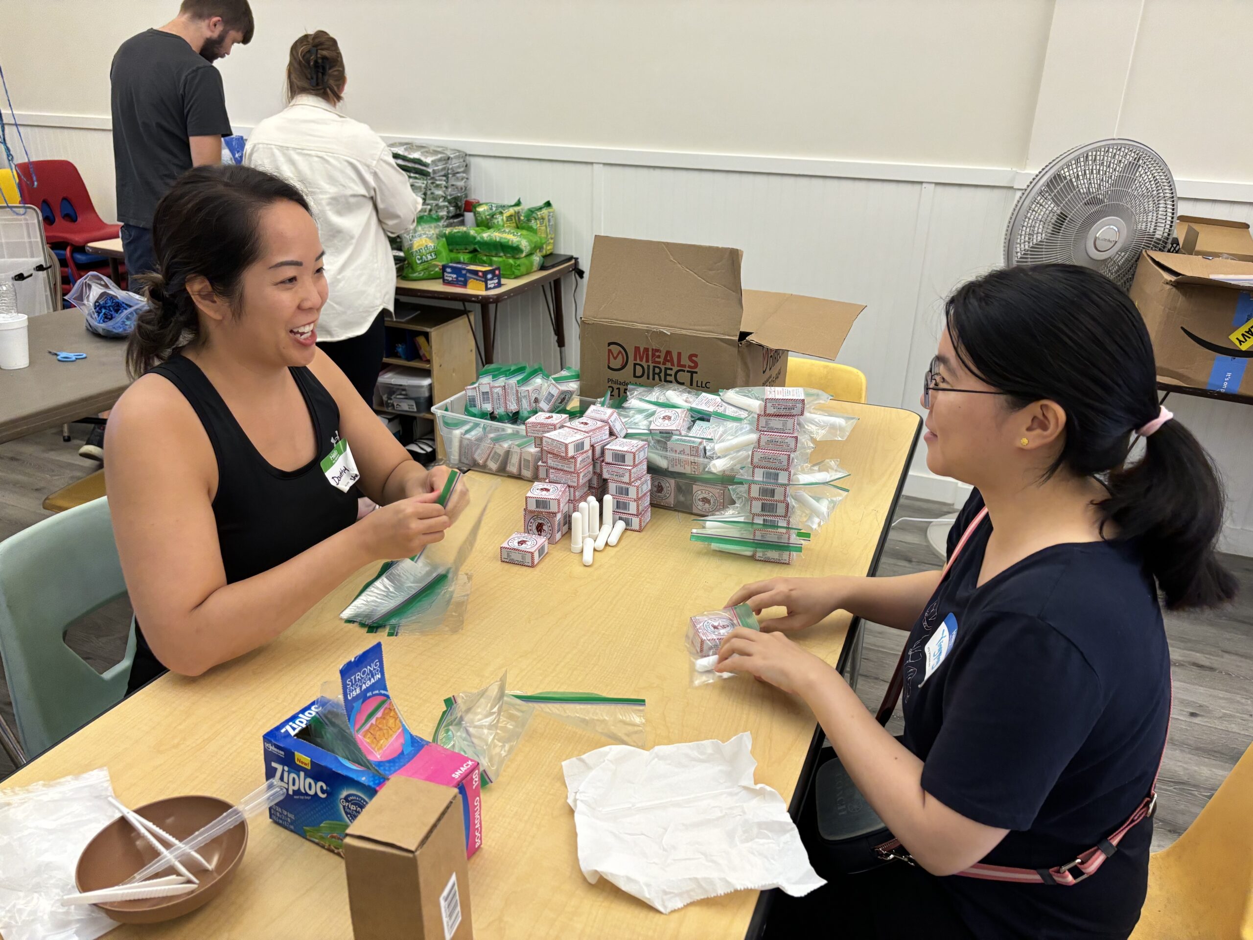 Dorothy Sheu and Yingying Lu sit at a table making scent sticks.