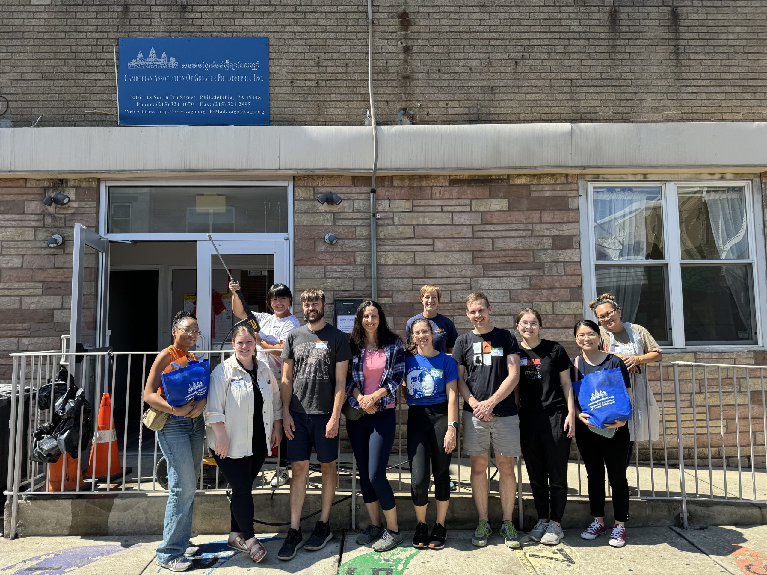 Nine volunteers from the PAIR Center pose with VIP leaders Julia Zielinski and Eddy Sacksith in front of the CAGP South Philly Center.