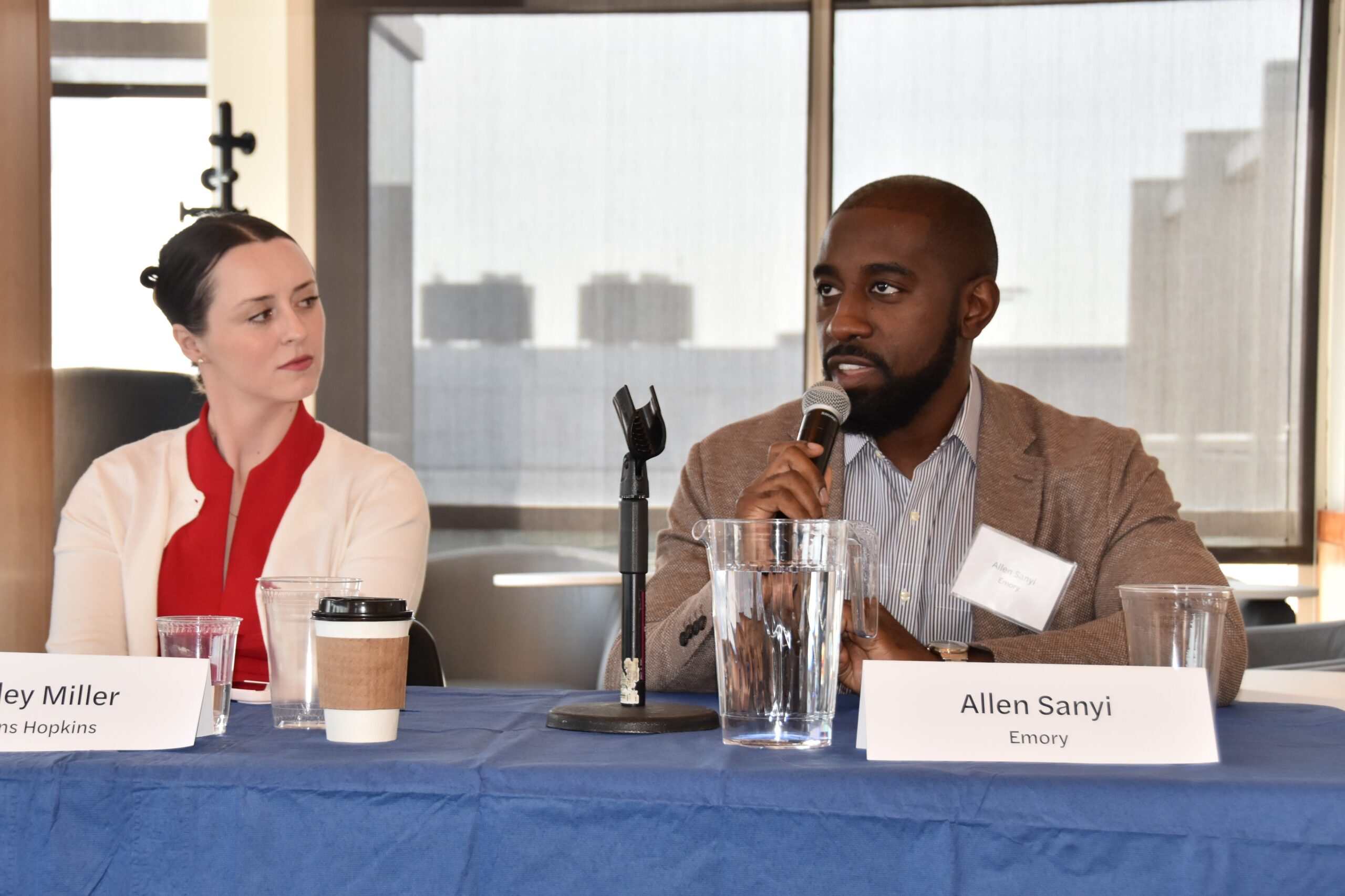 Allen Sanyi speaks into the microphone while on the panel, next to Hailey Miller.